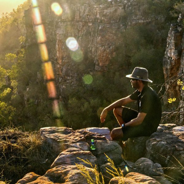 Man sitting on a cliff edge at sunset