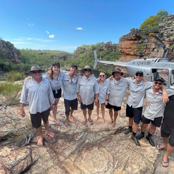 Crew of the Great Escape Co on a cliff near a helicopter